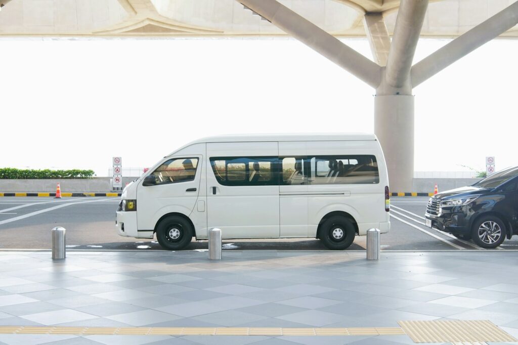 A white van waiting at an airport terminal pick-up area